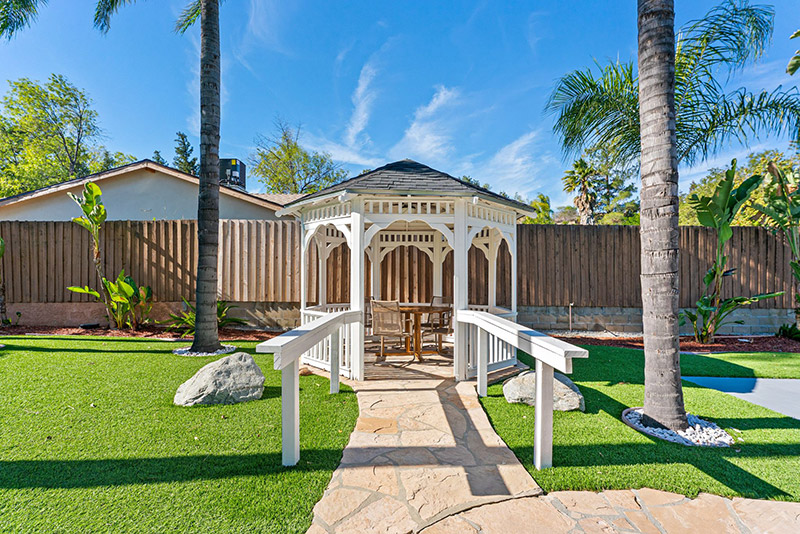 White gazebo connected to the lawn by a covered walkway
